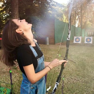 Genevieve Gaunt laughing while holding a bow and arrow